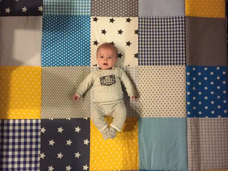 Een baby die een lichtgekleurde langermouwige blouse en gestreepte broek draagt.